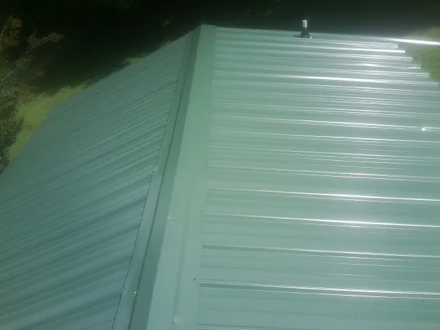 New green metal panels meeting at the ridge of a roof — Flat Roof Repair work by our crew in Lapaz