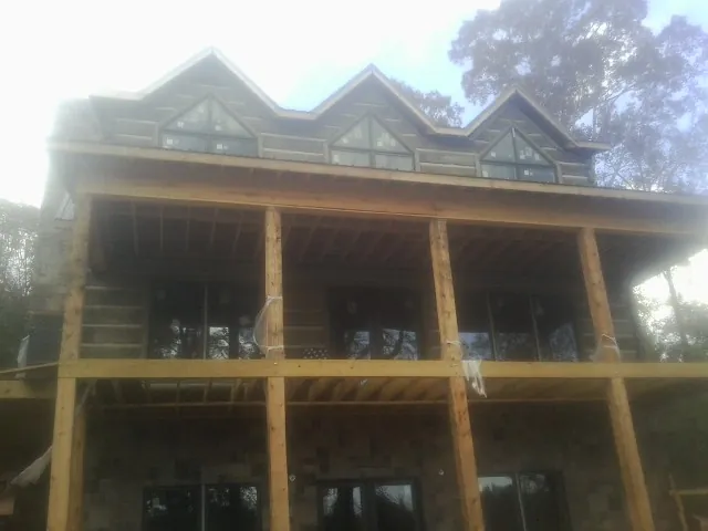 Dormers and porch framing on a large log home under construction — Roof Coating work by our crew in Lapaz