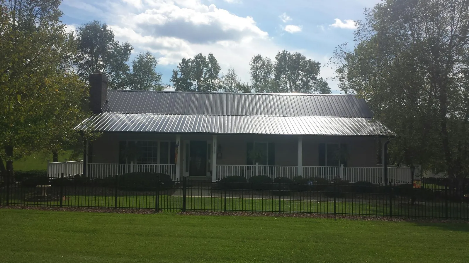 Gray metal roof on a brick ranch with a full width front porch — Gutter Guard Installation work by our crew in Lapaz