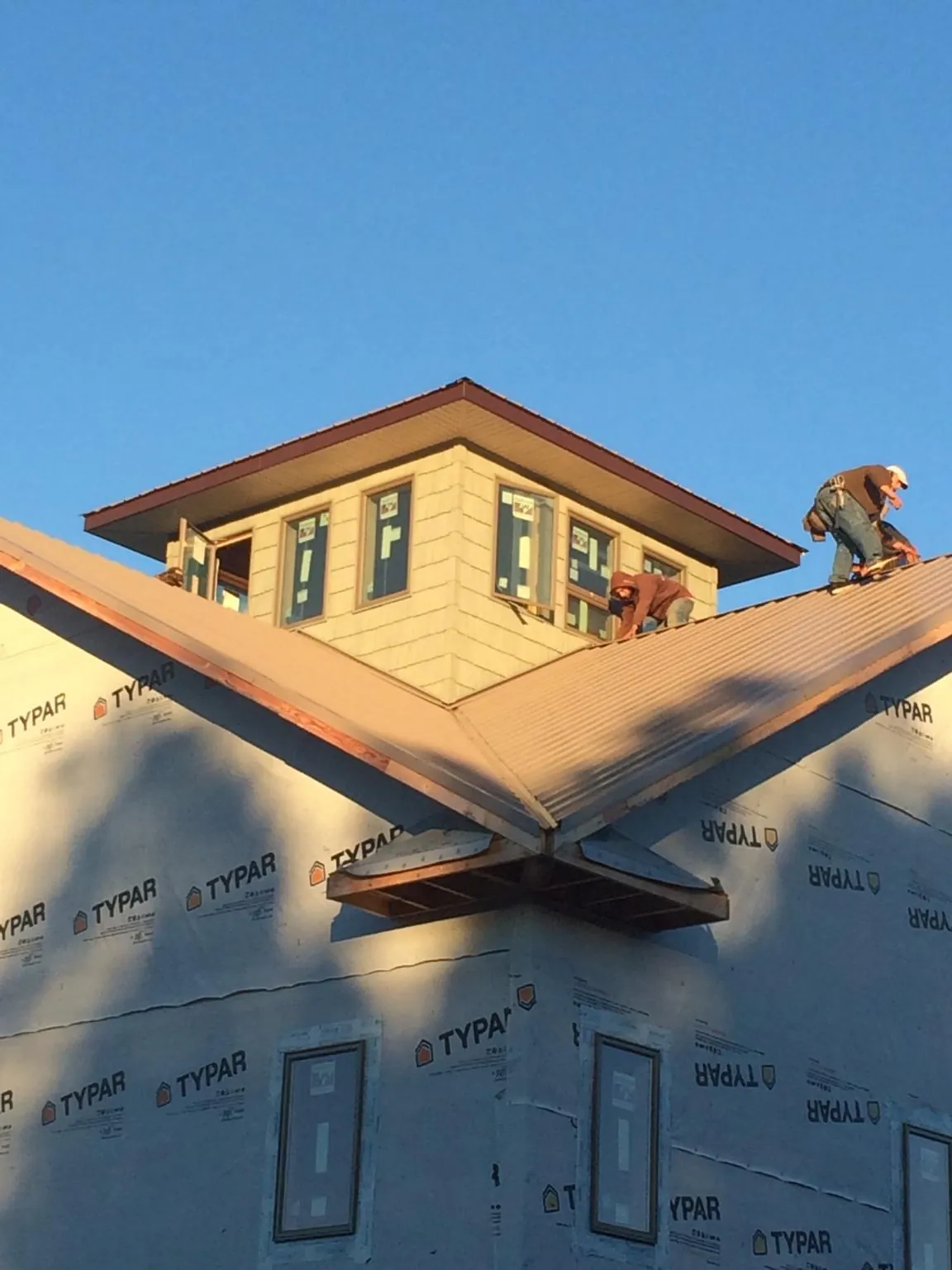 Roofers working around a rooftop cupola on a new metal roof at sunset — Roof Waterproofing in Lapaz by Roofing Brothers